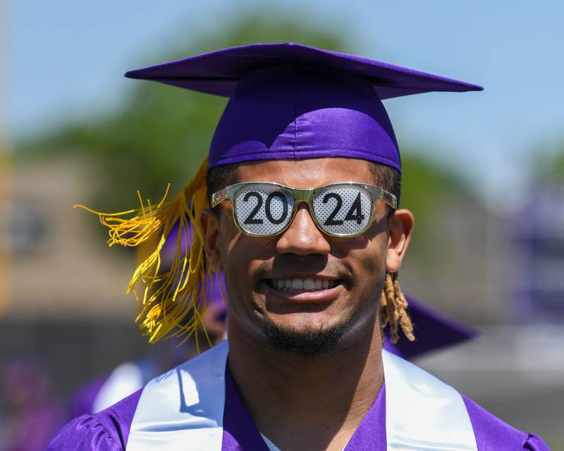 Downers Grove North senior Noah Battle is all smiles after arriving at his seat and pulling out his sunglasses during the processional portion of graduation on Sunday May 19, 2024, held at Downers Grove North High School.