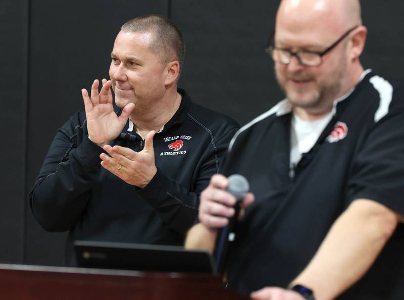 Indian Creek girls basketball head coach Paul Muchmore applauds as some of the accomplishments of his past teams are read off by athletic director Ehren Mertz Tuesday, Feb. 10, 2026, during a cermony held before Indian Creek took on Rosary. Muchmore, the longtime coach of the Timberwolves, was being honored at his last home game before retirement from coaching at the end of the season.