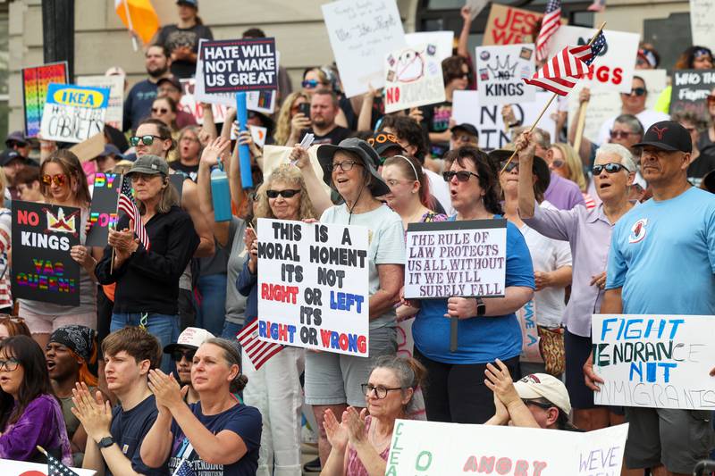 Protesters hold signs and applaud speakers as approximately 500 people gathered for a photo on the steps of the Kankakee County Courthouse during a ‘No Kings’ rally in Kankakee on Saturday, June 14, 2025, to protest actions by President Donald Trump.