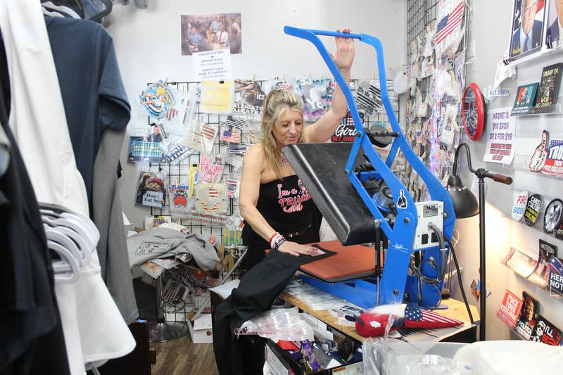 Trump and Truth Store owner Lisa Fleischmann irons on Trump-themed decals onto a shirt for a customer on July 13, 2025 in Huntley.