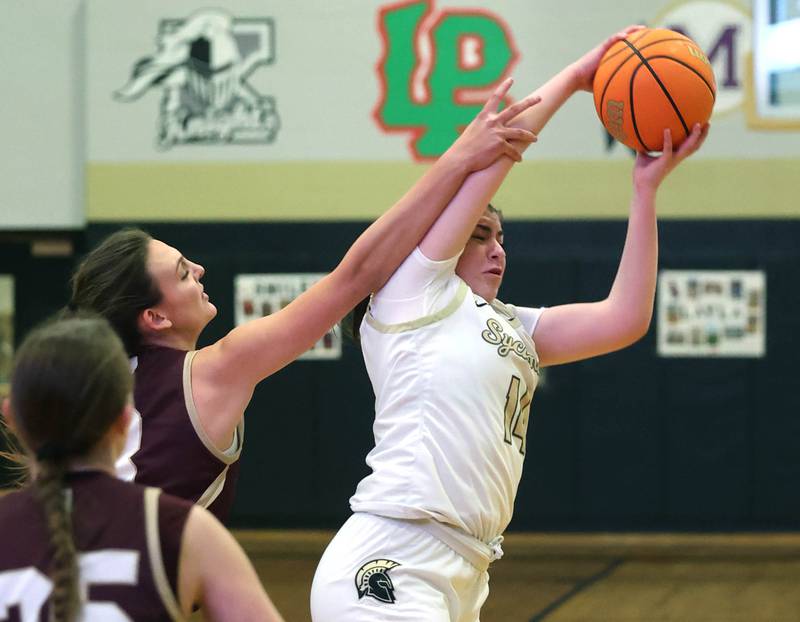 Sycamore's Norah Chami grabs a rebound in front of Morris' Lily Hansen during their game Tuesday, Jan. 13, 2026, at Sycamore High School.