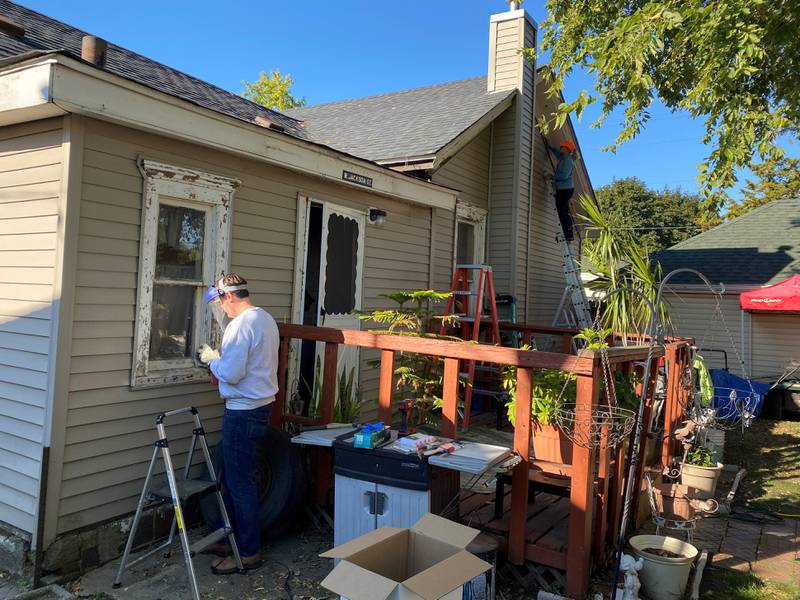 Labor of Love volunteers work on the windows of a Jackson Street home as part of Saturday's efforts.