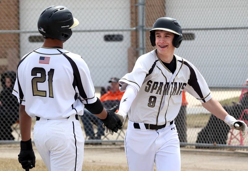 Sycamore's Jackson Macdonald (right) is greeted after scoring a run, by on deck hitter Tyler Townsend during their game against Byron Wednesday, March 26, 2025, at DeKalb High School. Sycamore’s home field was damaged in last week’s storms so today’s game was played on DeKalb’s field.