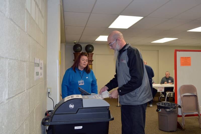 Chad Hammer, of Mt. Morris, turns in his ballot with the help of election judge Rose Medearis on Tuesday, Nov. 5, 2024, in the Mt. Morris Village Hall basement.