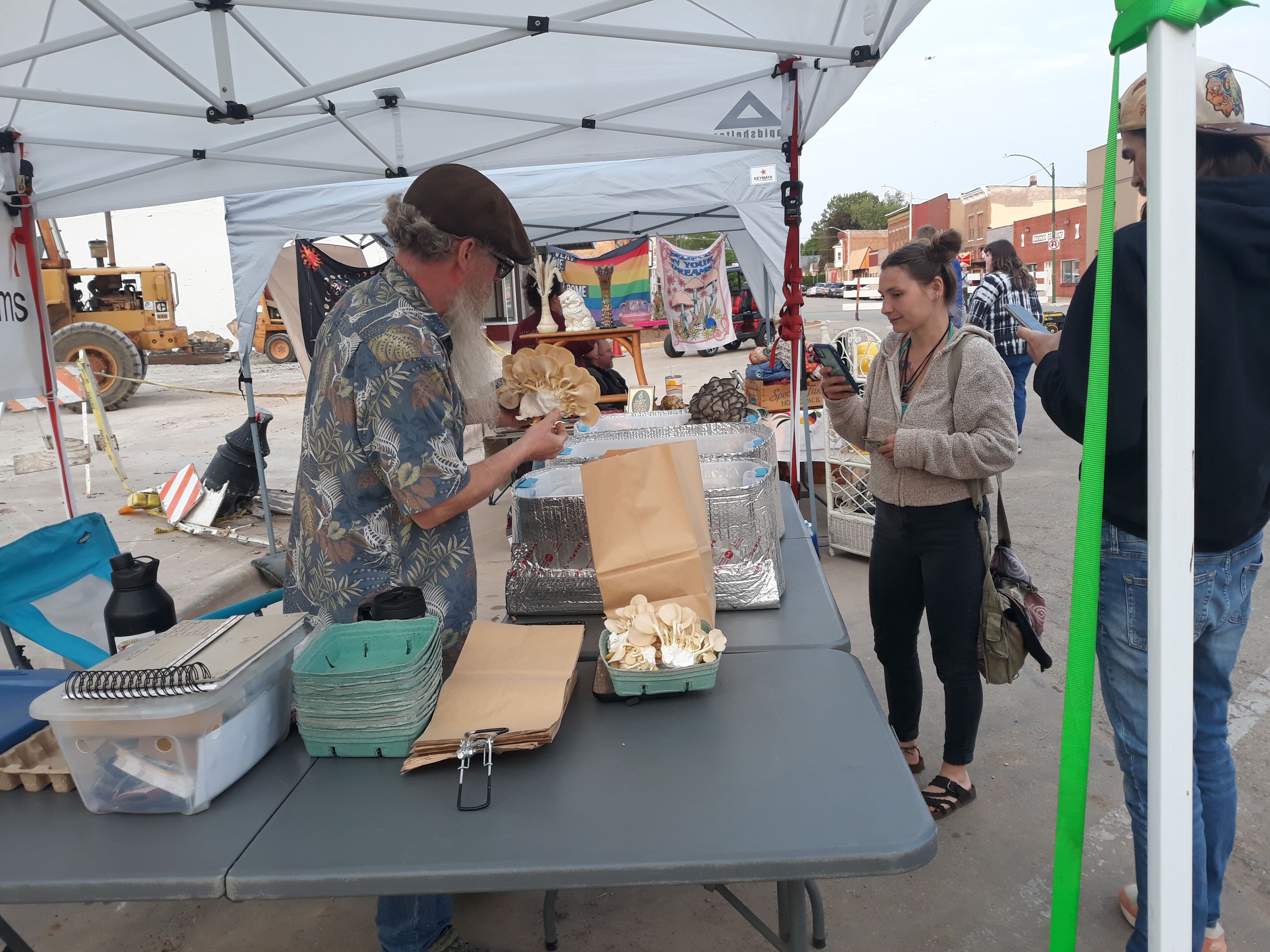 William Thomas of Meddling Sheep Mushrooms of Amboy waits on a customer Friday, May 19, 2023, who gets a picture herself during the first Friday Night Market in downtown Spring Valley.