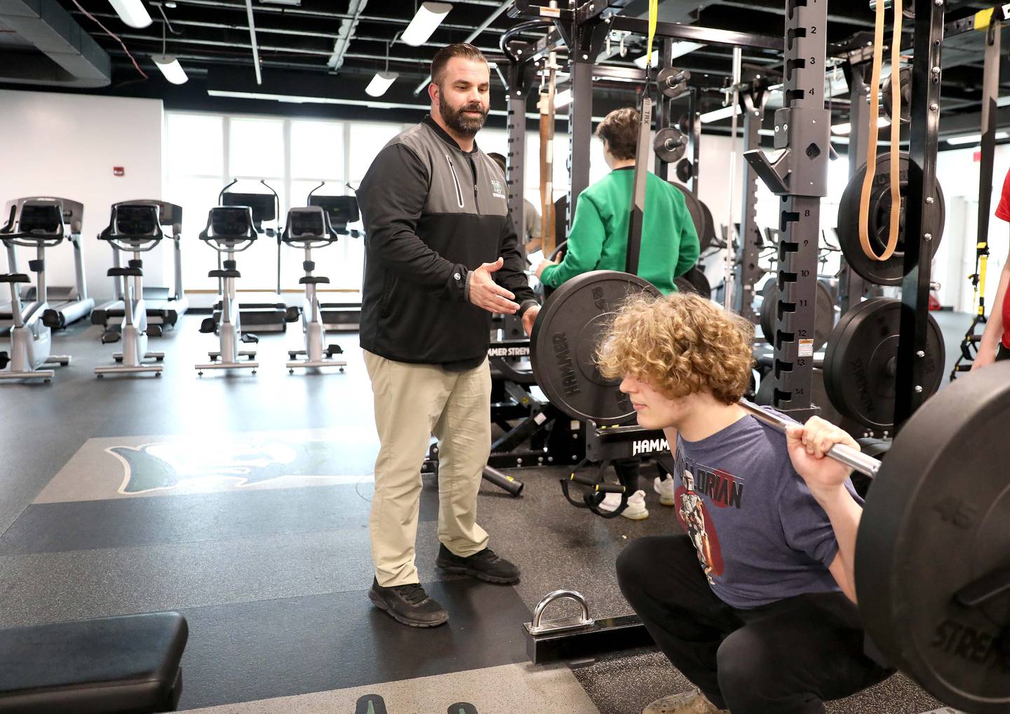 York High School teacher and wrestling coach Nick Metcalf works with senior James Casey in the school’s weight room.