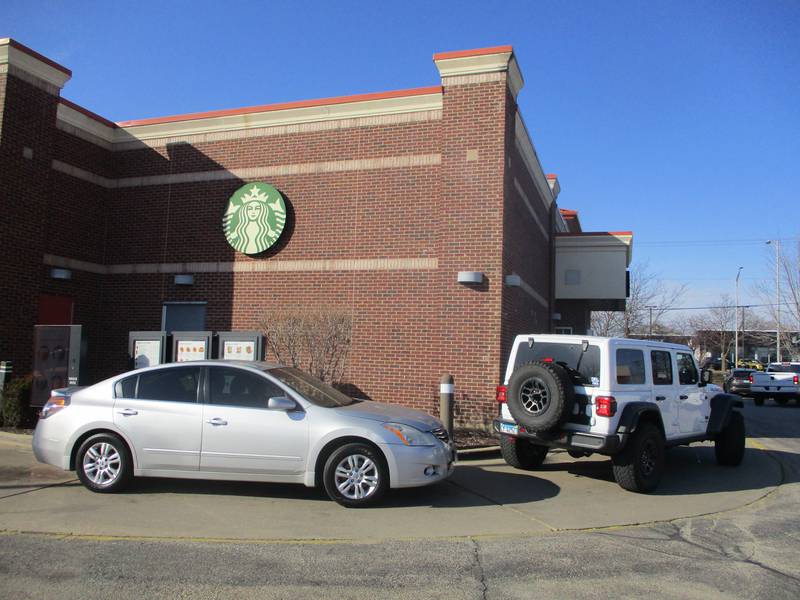 Vehicles containing drive-thru Starbucks customers wind around the small strip mall that includes the coffee shop at Jefferson Street and Caterpillar Drive in Joliet. Feb. 25, 2024.
