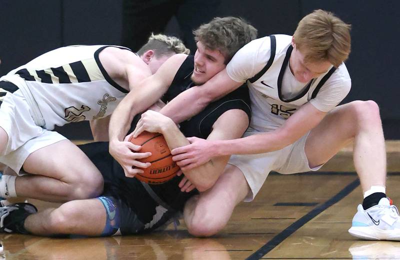 Kaneland's Parker Violett is sandwiched between Sycamore's Thatcher Friedrichs (right) and Teague Hallahan as they fight for a loose ball during their game Friday, Feb. 10, 2023, at Sycamore High School.