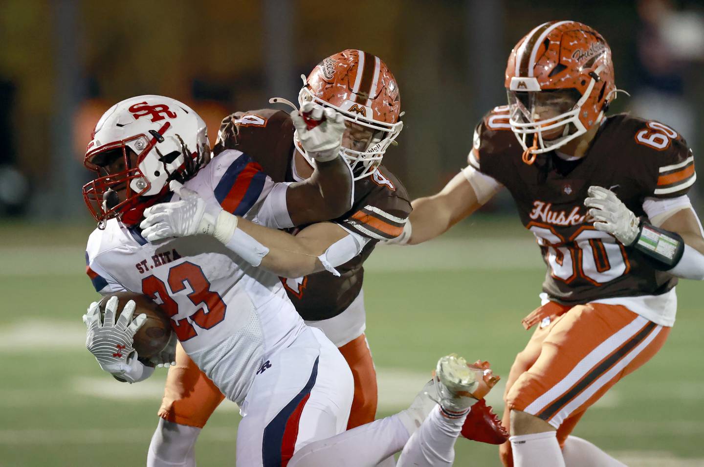 Hersey's Cheydon Georgacakis (4) and  Spiro Zarafonitis (60) wrap up St. Rita's Brandon Johnson Jr. (23) during the IHSA Class 6A Football Quarterfinal Saturday, Nov. 15, 2025 in Arlington Heights.