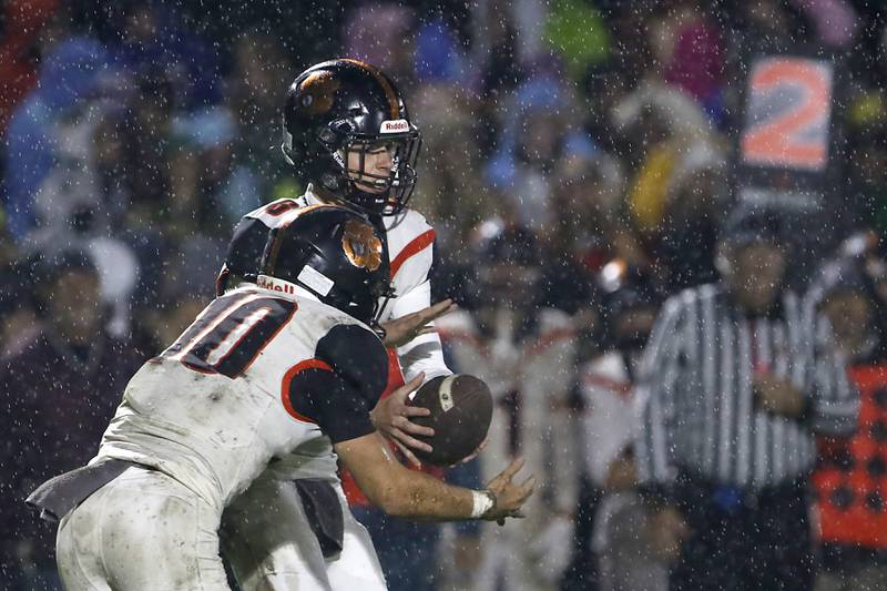 Crystal Lake Central's Abraham Quinn hands the ball off to his teammate, Griffin Buehler, during a Fox Valley Conference football game against Prairie Ridge on Friday, Oct. 13, 2023, at Prairie Ridge High School in Crystal Lake.