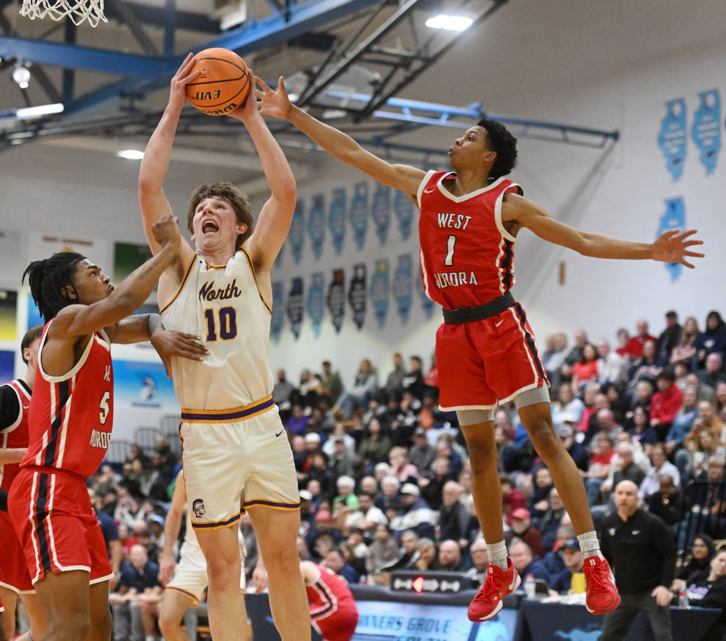Downers Grove North's Bobby Grganto makes a strong move to the basket between West Aurora's Terrence Smith, left, and Travis Brown during the Class 4A Downers Grove South regional final on Friday, Feb. 28, 2025 in Downers Grove.