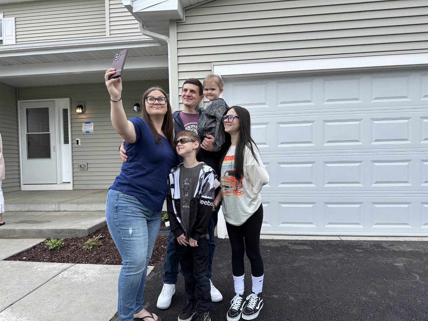 Michael Shelton and his fiancé Amanda Corbin take selfies with their three children, Kaylee Shelton, 13; Brandon Shelton, 11 and Ava Shelton, 3, outside their new Habitat for Humanity home in Wonder Lake on Saturday, May 13.