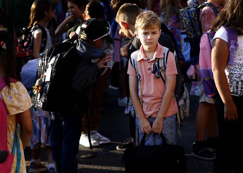 Third-grader Adam Zmuda waits for school to start with other students on the first day of school at Olson Elementary School in Woodstock on Wednesday, Aug. 14, 2024,