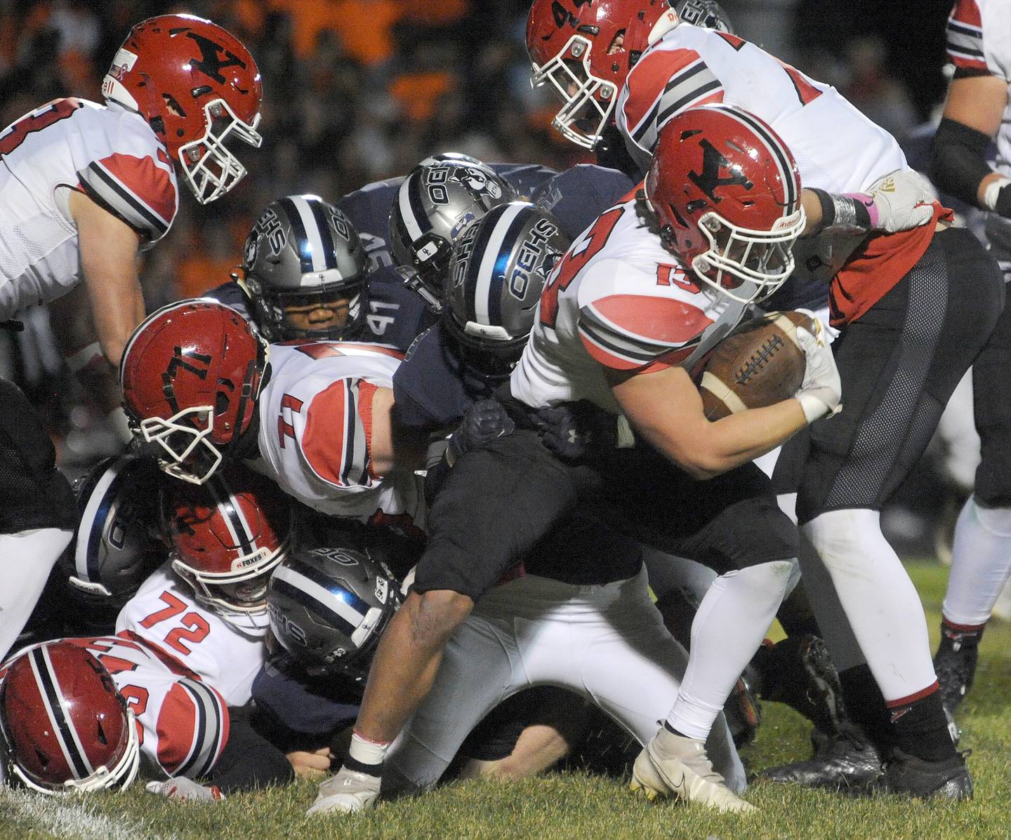 Yorkville running back Ben Alvarez (13) escapes from a pile of Oswego East defenders during a varsity football game at Oswego East High School on Friday, Oct. 7, 2022.