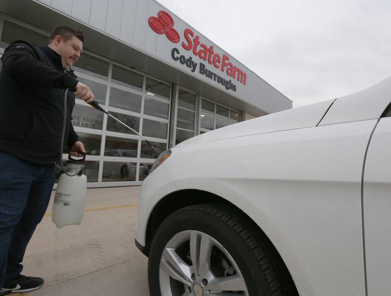 Matt Stabb, manager at Cody Burroughs State Farm in La Salle, washes down a vehicle using hydrogen peroxide and vinegar the day after the Carus Chemical fire on Thursday, Jan. 12, 2023 in La Salle.