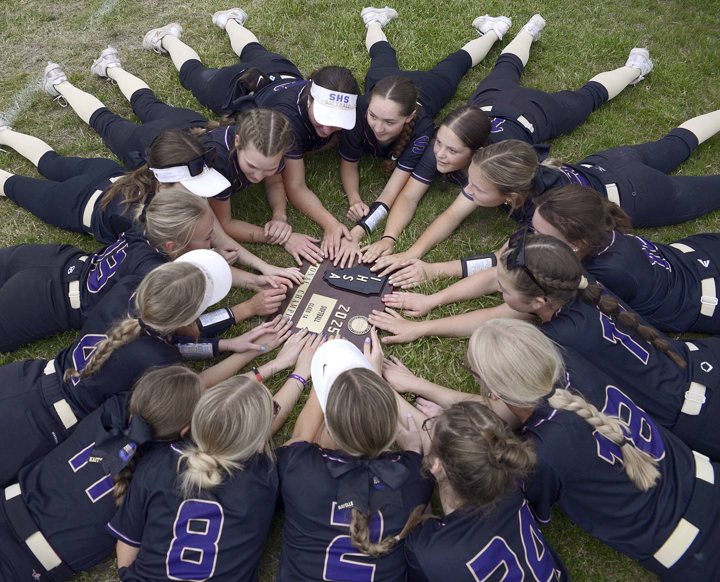 The Lady Serena Huskers gather in the outfield around their sectional plaque after defeating Marquette Friday at Serena.
