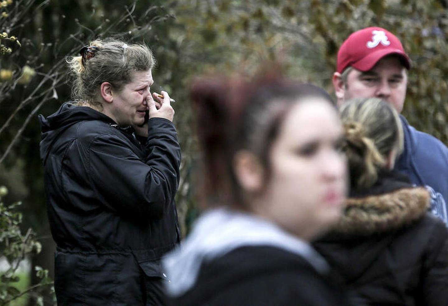 Friends of Kaitlyn Kearns, a 24-year-old bartender from Joliet, cry Nov. 16, 2017, along East Washington Street as county investigators search the clubhouse belonging to the Outlaws in Joliet, Ill. Kearns' body was found Thursday in a rural area of Kankakee County, according to a sheriff’s office news release.