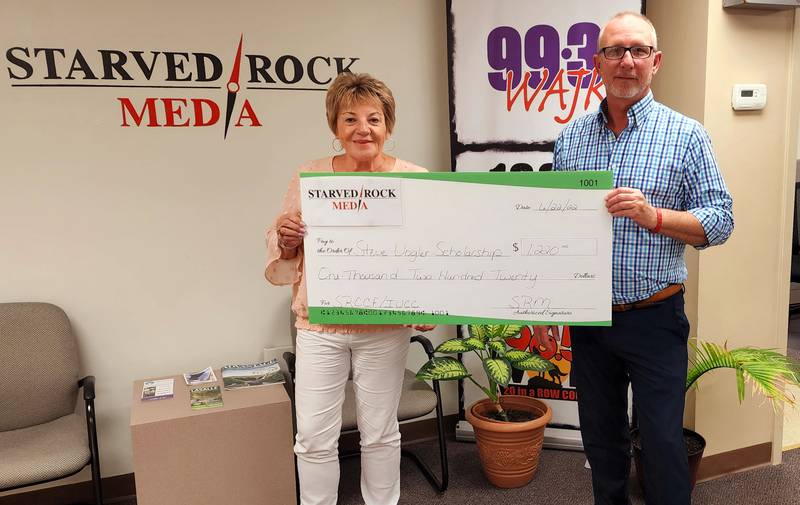 Pamela Beckett, Starved Rock Country Community Foundation co-founder, accepts a check for the Steve Vogler Scholarship from Starved Rock Media President John Spencer.