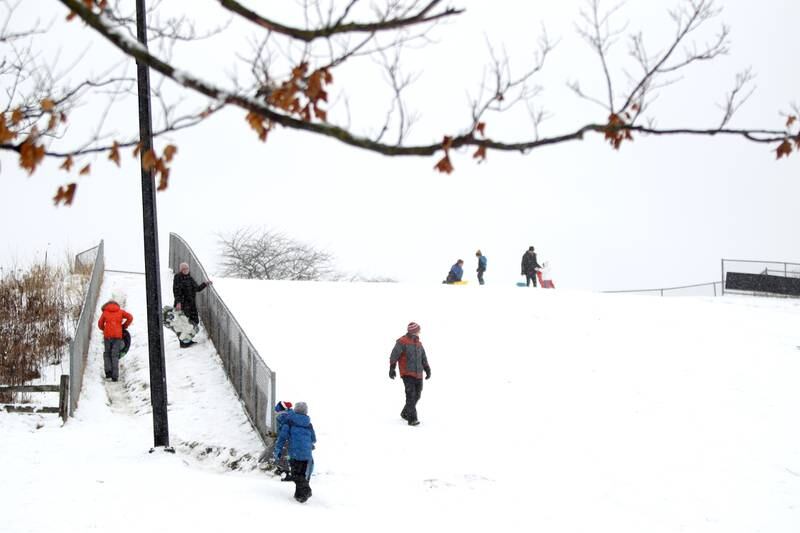 Sledders climb the hill at Northside Park in Wheaton on Wednesday, Jan. 25, 2023.