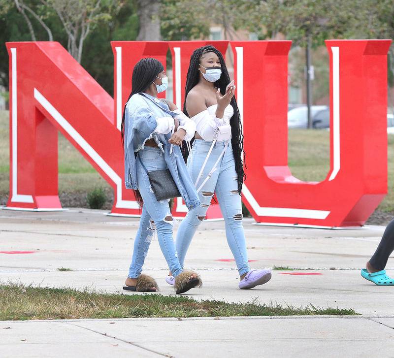 Brittni Adams (left) and Nakiah Wilkes, both freshman from Chicago, wear masks as they walk past the NIU sign at Northern Illinois University Tuesday afternoon. Masks can be seen on students all over campus as they adjust to attending classes amid the pandemic.