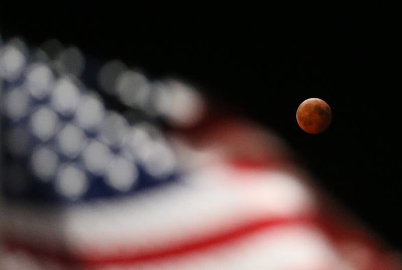 An American flag blows in the wind duiring a total lunar eclipse on Friday, March 14, 2025 at City Hall Park in Princeton. A lunar eclipse occurs when the Sun, Earth, and Moon align so that the Moon passes into Earth’s shadow. When the Moon is within the umbra, it appears red-orange. Lunar eclipses are sometimes called “Blood Moons” because of this phenomenon. The next visible one in Illinois will not occur until March 3, 2026.