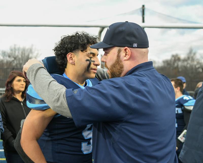 Nazareth Academy running back and linebacker coach Mike Stella and Nazareth Academy's Noah Sanchez (9) hug after falling short to Fenwick during the 6A semifinals overtime game on Saturday Nov. 22, 2025, held at Nazareth Academy High School in La Grange Park.