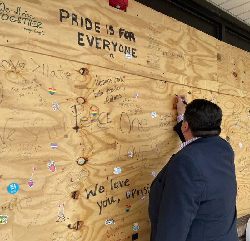 Illinois Gov. JB Pritzker leaves his mark on the window board at UpRising Bakery and Cafe at Lake in the Hills; the governor made a surprise visit to the cafe Friday afternoon, which has received harassment over the past month, including outright vandalism, over a planned drag brunch show, which was rescheduled for this upcoming Sunday.