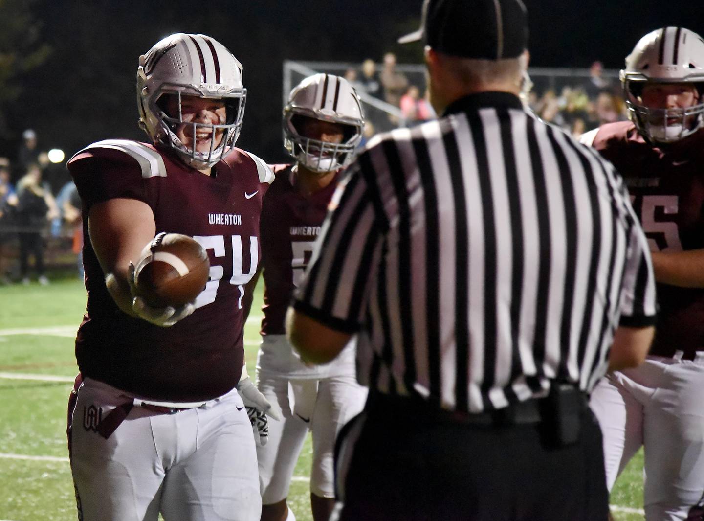 Wheaton Academy's Jake Figurski, a 275-pound nose guard, hands the ball to a referee after scoring a touchdown against St. Edward in a football game in West Chicago on Thursday, October 7, 2021.
