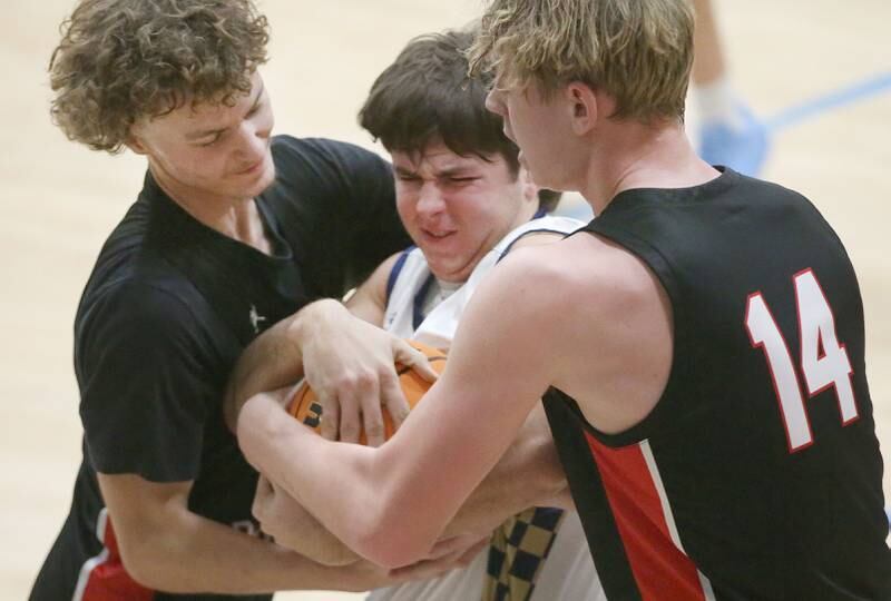 Marquette's hangs on to force a jump ball with Earlville's Gavin Guelde and Adam Waite on Friday, Jan. 3, 2025 in Bader Gym at Marquette High School.