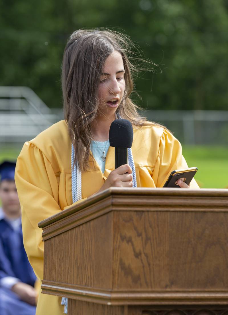 Marquette Academy Class of 2022 Salutatorian Josephine Eager wraps up her speech while reviewing her iPhone Sunday, May 29, 2022, after the wind blew away her paper copy and her cap.