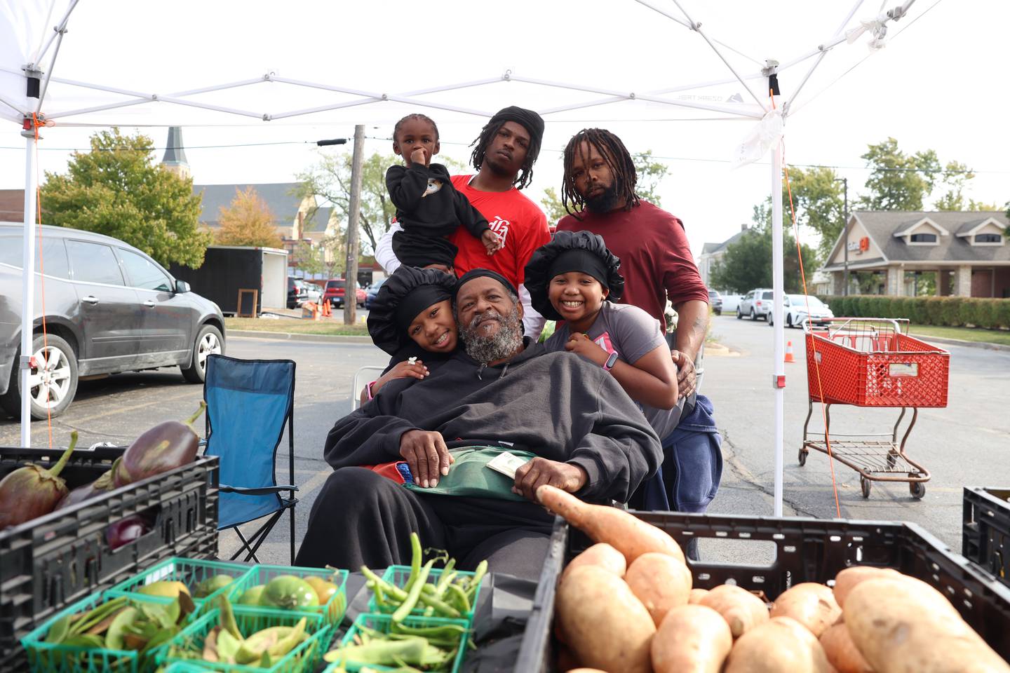 Pembroke produce farmer John Thurman, center, poses for a photo with family members at the Kankakee Farmers' Market on Saturday, Oct. 18, 2025. His son, Jacob Thurman, stands to the back right, and grandson, John Thurman, 19, back center, holds 3-year-old Ja'Shawn Jefferson. Granddaughters Gabby, 8, left, and Isabella, 9, rest on his shoulders.