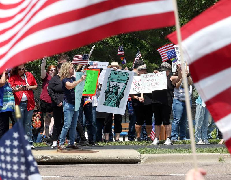Protesters chant and wave flags along Sycamore Road Saturday, June 14, 2025, during a No Kings rally at Hopkins Park in DeKalb. The group was protesting the policies of President Donald Trump and his administration.