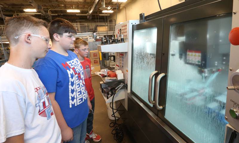 Students watch a machine make parts in the machining class during the Area Career Center Hands-On Showcase on Thursday, June 8, 2023 at La Salle-Peru Township High School.