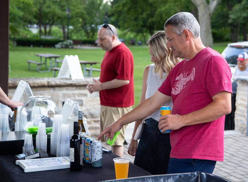 Eric, right, and Rebecca DePorter of Glen Ellyn choose a beer from the Beer Cellar tent during Thirsty Thursday on the Deck at the Lake Ellyn Boathouse in Glen Ellyn on July 20, 2023.