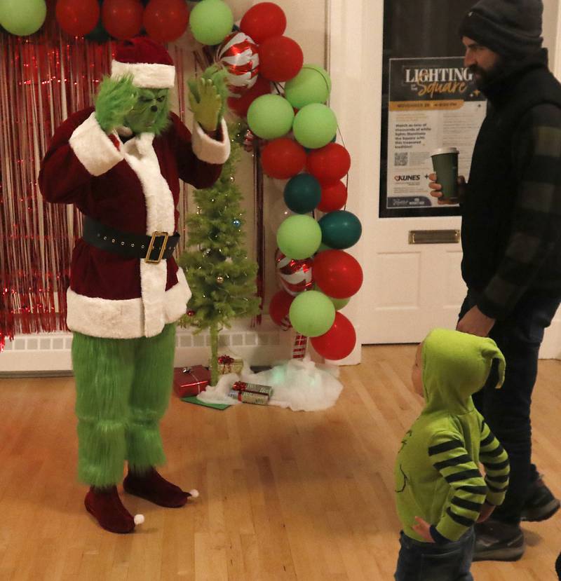 The Grinch interacts with Lucas Lichtenberger, 3, during the Lighting of the Square Friday, Nov. 29, 2024, in Woodstock. The annual holiday season event featured brass music, caroling, free doughnuts and cider, food trucks, festive selfie stations and shopping.