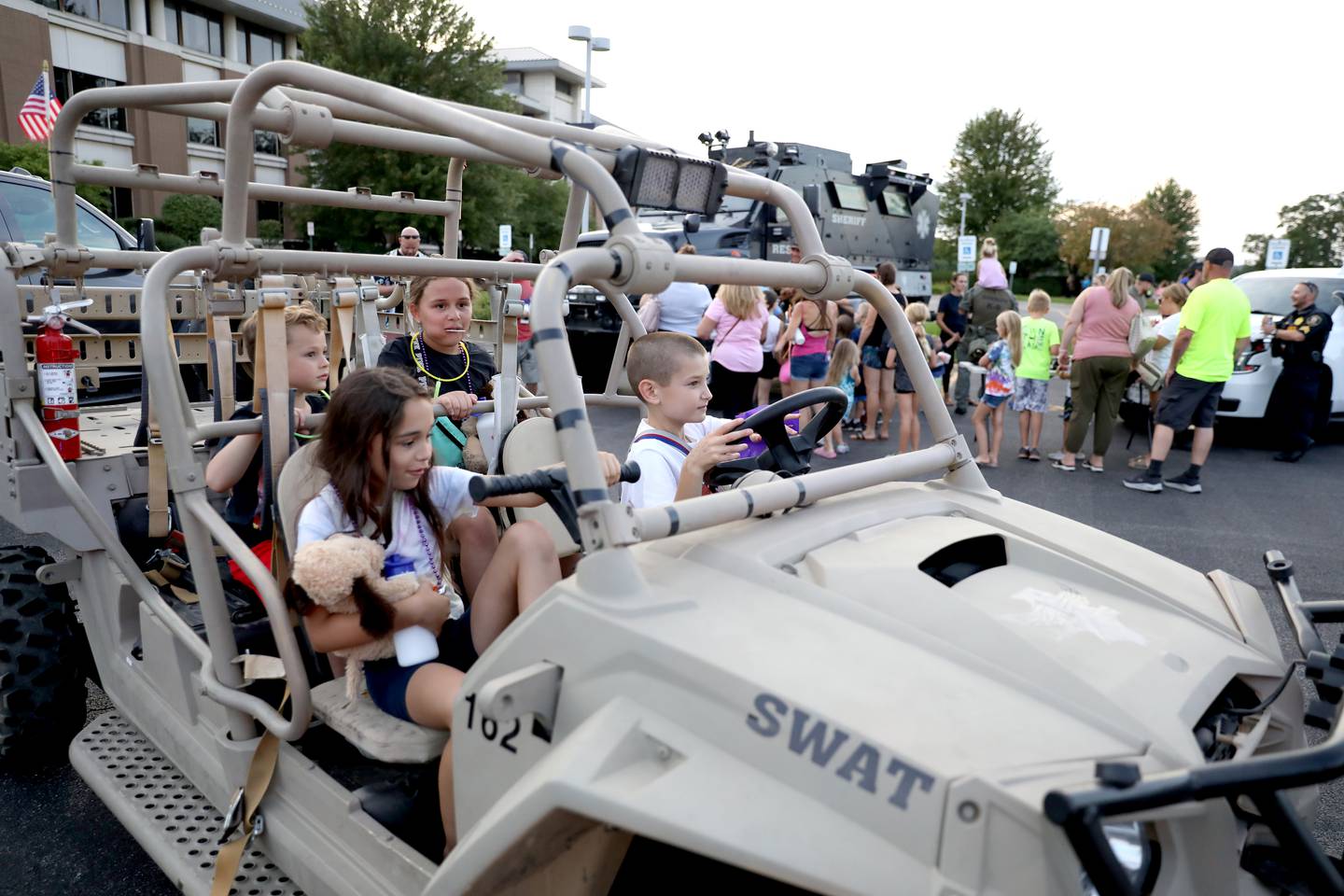 (Clockwise from bottom right) Liam Deaton, 10, Mariela Baumbach, 9, Wyatt Deaton, 6, and Izzy Baumbach, 10, all of Elburn, pretend to drive a SWAT vehicle during the Kane County Sheriff’s Office National Night Out event in St. Charles on Tuesday, Aug. 1, 2023. The community-building event began nationally in 1984.