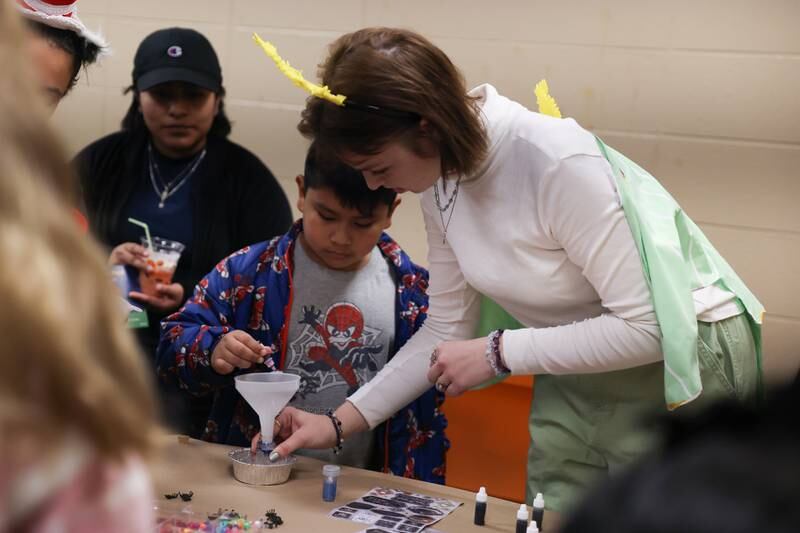 Olivia Kuncis, right, a student at Lewis University helps Luis Roman, 8, from Joliet make a potion at the STEAM Spooktacular hosted by the After the Peanut Foundation on Wednesday at Lewis University.