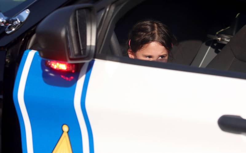 Kayla Dissen, 3, of Crystal Lake peers over the top of a police cruiser door during National Night Out activities in downtown Crystal Lake on Thursday, Aug. 7, 2025.