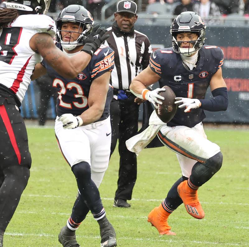 Chicago Bears quarterback Justin Fields rolls out as Chicago Bears running back Roschon Johnson blocks an Atlanta Falcon defender during their game Sunday, Dec. 31, 2023, at Soldier Field in Chicago.