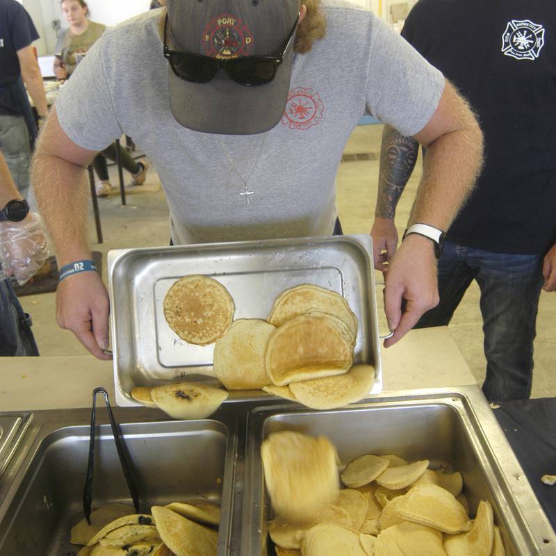 Firefighter Cody Alguire brings pancakes to pans at he Port Byron-hosted Great River Tug Fest across the Mississippi on Saturday, Aug. 10, 2024