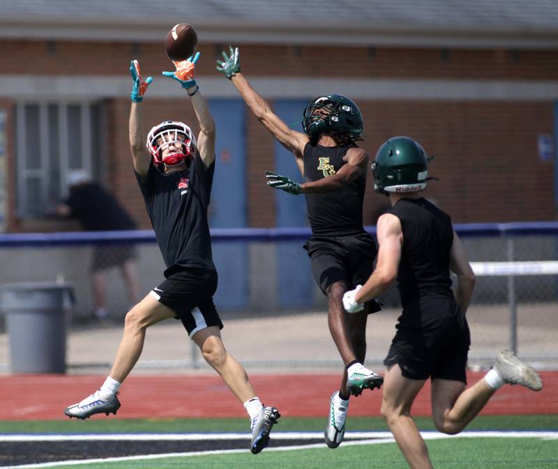 A Yorkville player (left) reaches for the catch during a 7-on-7 football game against Elk Grove at St. Charles North on Thursday, June 22, 2023.