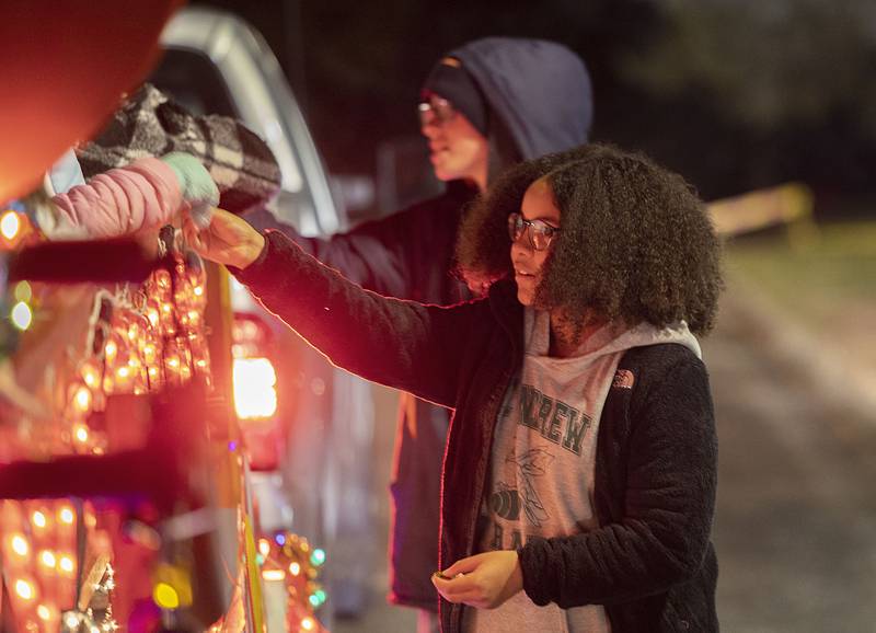 Sienna Thompson, sixth-grade student and student council secretary at St. Andrew’s School, hands out chocolate coins at the school’s lighted holiday display at Centennial Park in Rock Falls. On Sunday, the Coloma Park District offered horse-drawn carriage rides to see the lights in the park. The district will be offering more rides on Dec. 9.