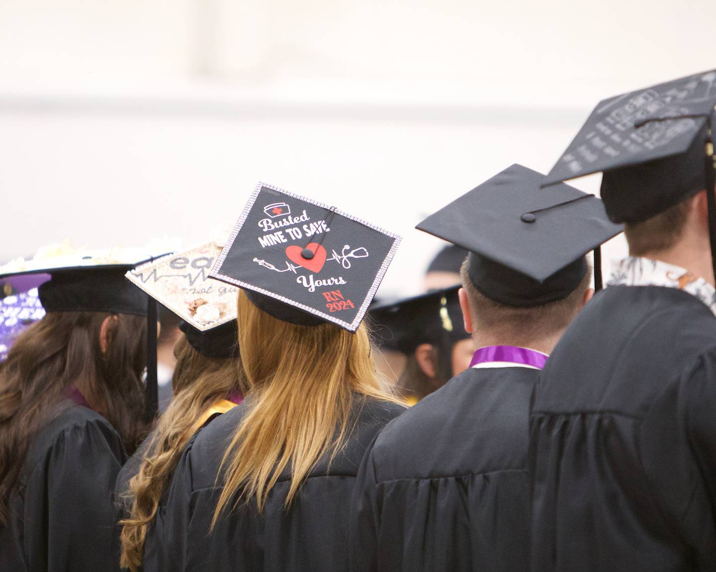 A nursing graduate displays a decorated cap reading, "Busted mine to save yours" at McHenry County College commencement on Saturday, May 11, 2024, in Crystal Lake.