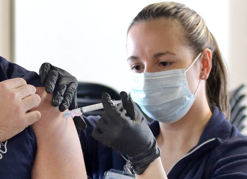 A City of DeKalb firefighter receives an injection of the Moderna COVID-19 vaccine from DeKalb County Health Department public health nurse Alex Diehl Thursday in DeKalb.