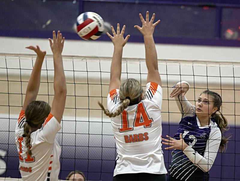 Dixon’s Solis Thompson spikes the ball against DeKalb’s Camryn Hilliard (left) and Brooklynn Siebrasse Tuesday, Sept. 5, 2023 in a game at Dixon High School.