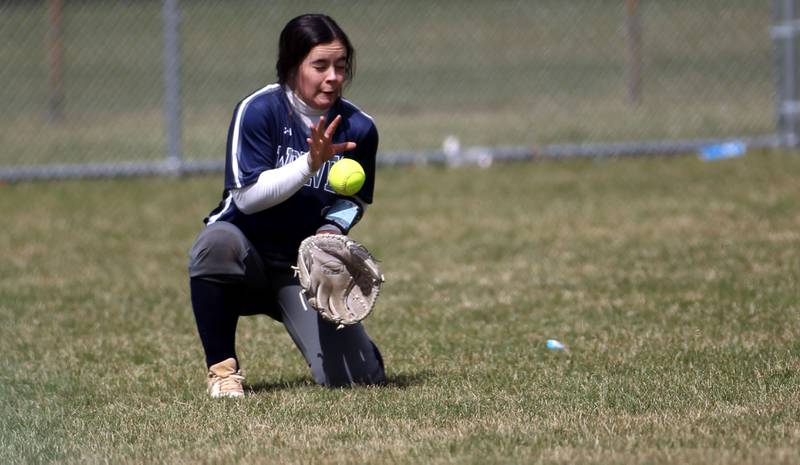 Oswego East’s Mia Corres attempts to scoop up a ground ball in the outfield during a game at Waubonsie Valley on Friday, April 1, 2022.