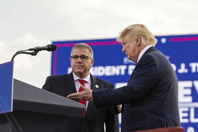 Former President Donald Trump, right, ushers gubernatorial candidate and state Sen. Darren Bailey to the podium at a rally at the Adams County Fairgrounds in Mendon, Ill., Saturday, June 25, 2022. (Mike Sorensen/Quincy Herald-Whig via AP)