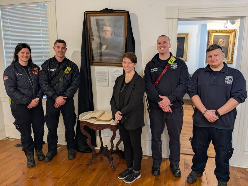 (From left) Princeton Fire Department team members Allysen Jacobsen, Eli Van Autreve, Bureau County History Center curator Jessica Gray, Bryan Berlin and Frank Filippi. Members visited to see the portrait of Wright Seaman as well as the original book of meeting minutes for the department. Seaman was the first Fire Chief in Princeton but was killed during the Civil War’s Battle of Shiloh.