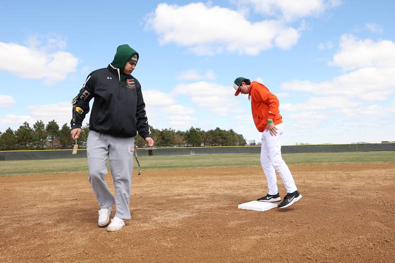 Plainfield East’s Caleb Soliz, left, and Joshua Keller place the base pads before the game against Downers Grove North. Friday, April 1, 2022, in Plainfield.