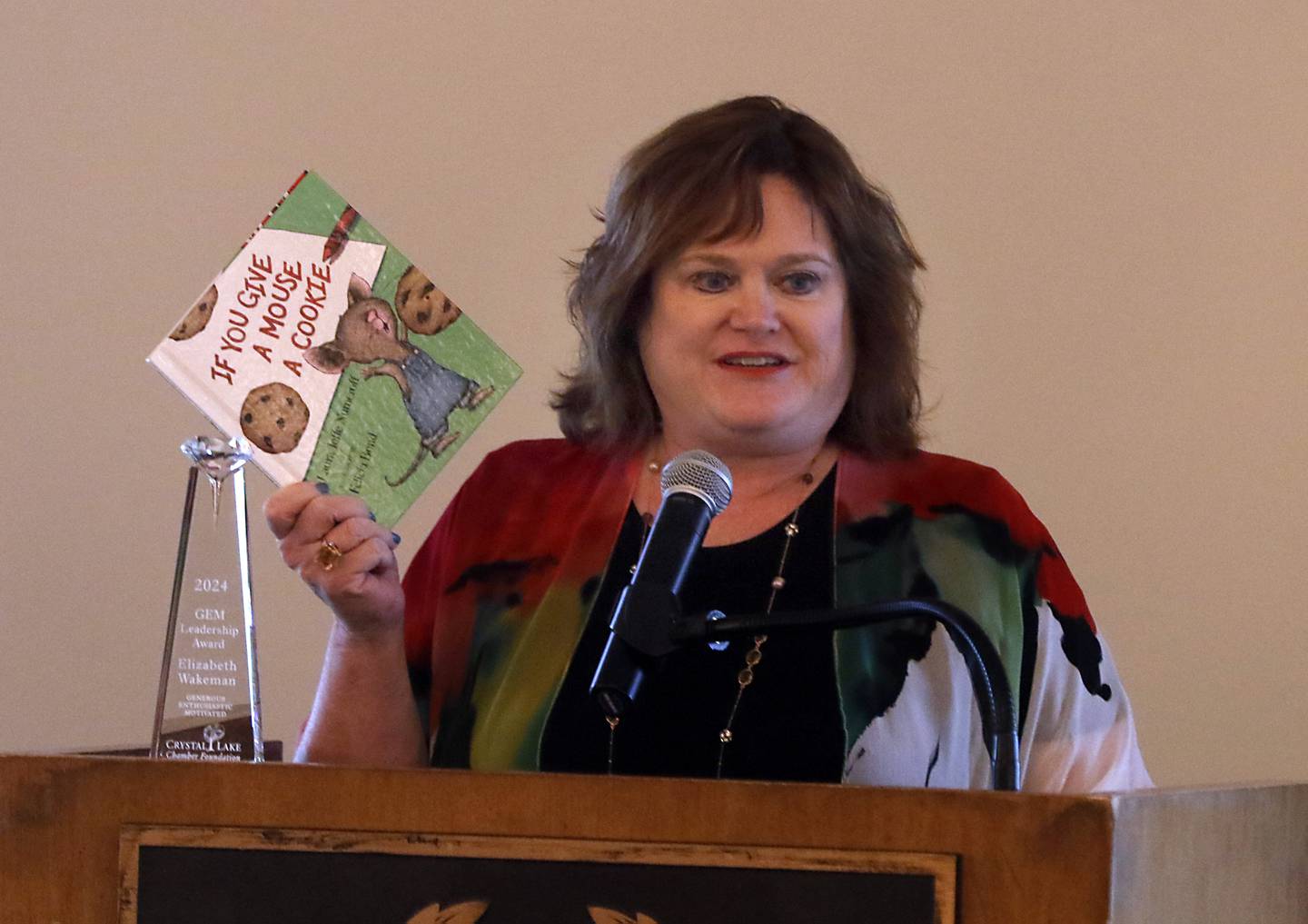 GEM award winner Elizabeth Felt Wakeman holds up the book “If You Give A Mouse a Cookie” during her speech at the Crystal Lake Chamber Foundation's 11th Annual GEM Awards Leadership Celebration on April 18, 2024, at the Boulder Ridge Country Club in Lake in the Hills. This year's award winners are Elizabeth Wakeman, of Wakeman Law Group, PC.; Randy Smith, of General Kinematics Corporation; and SHAW Media/The Northwest Herald.